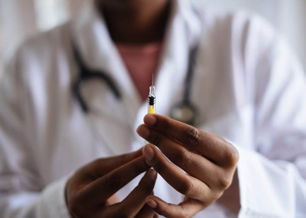 Doctor holding a needle with vaccine