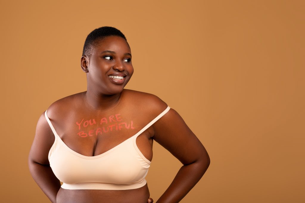 Black woman smiling with you are beautiful written on her body
