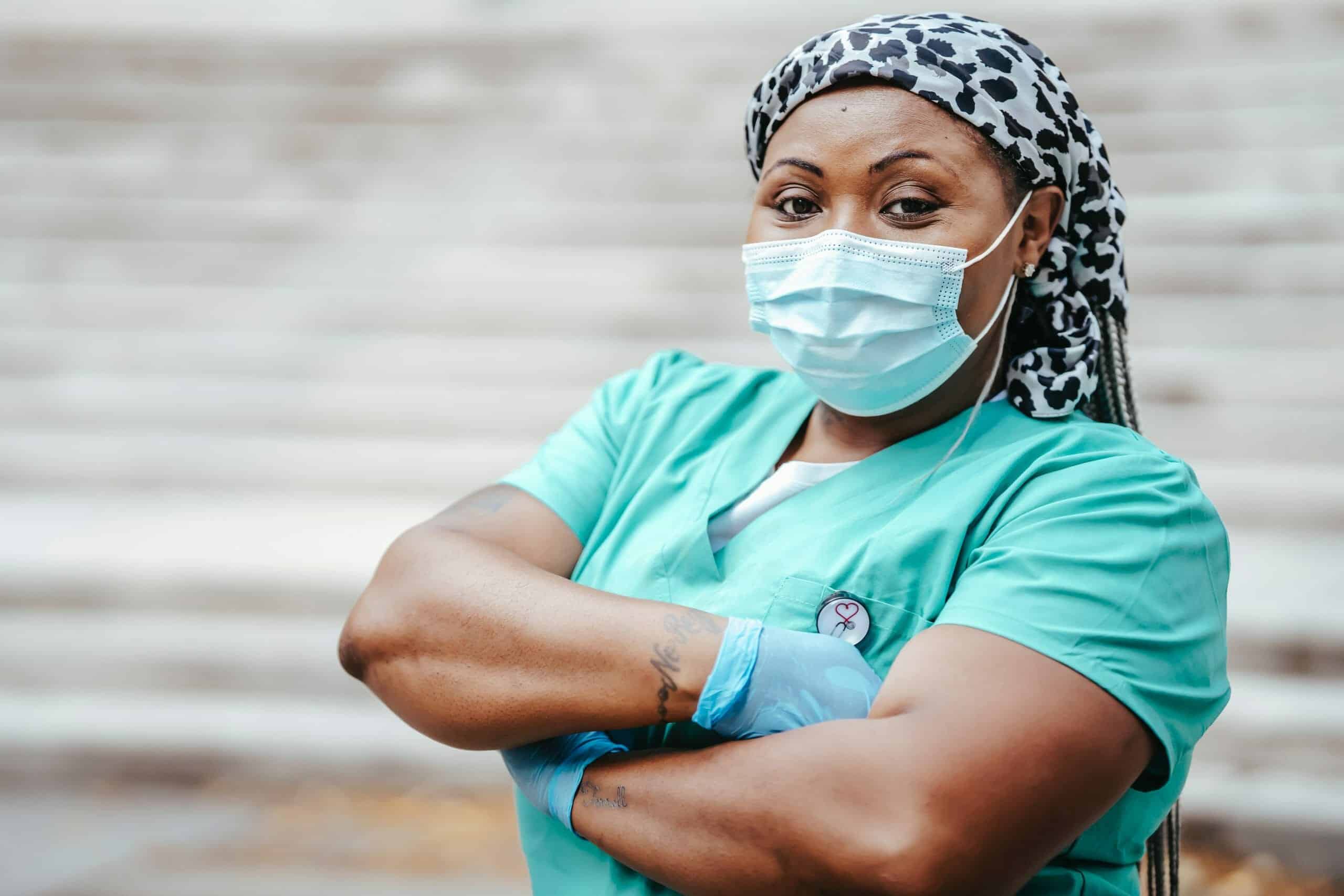 Black female doctor in uniform with visible tattoos on arms