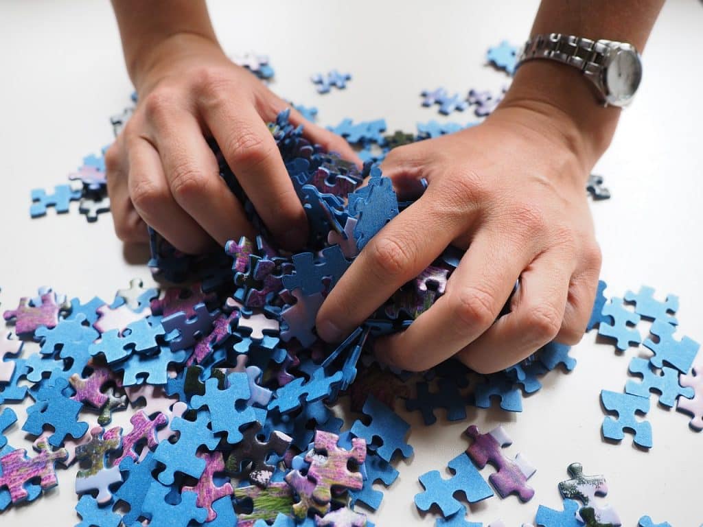 A person clutching puzzle pieces, showing how we all are trying to figure out the puzzle of life