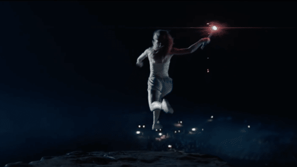 The female in the image is jumping off a cliff whilst holding a torch.