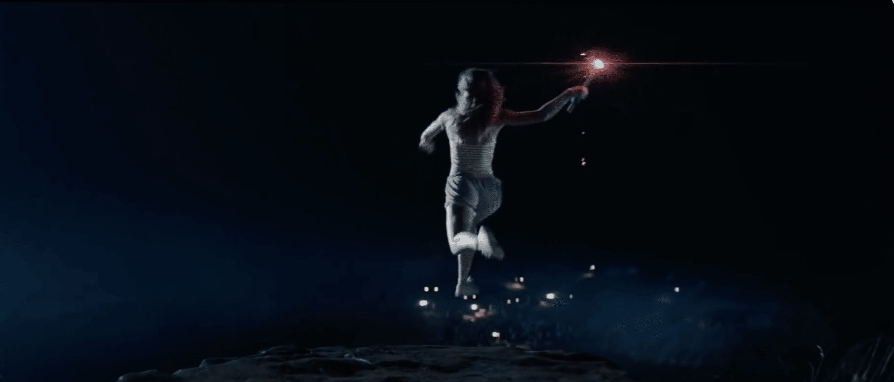 The female in the image is jumping off a cliff whilst holding a torch.