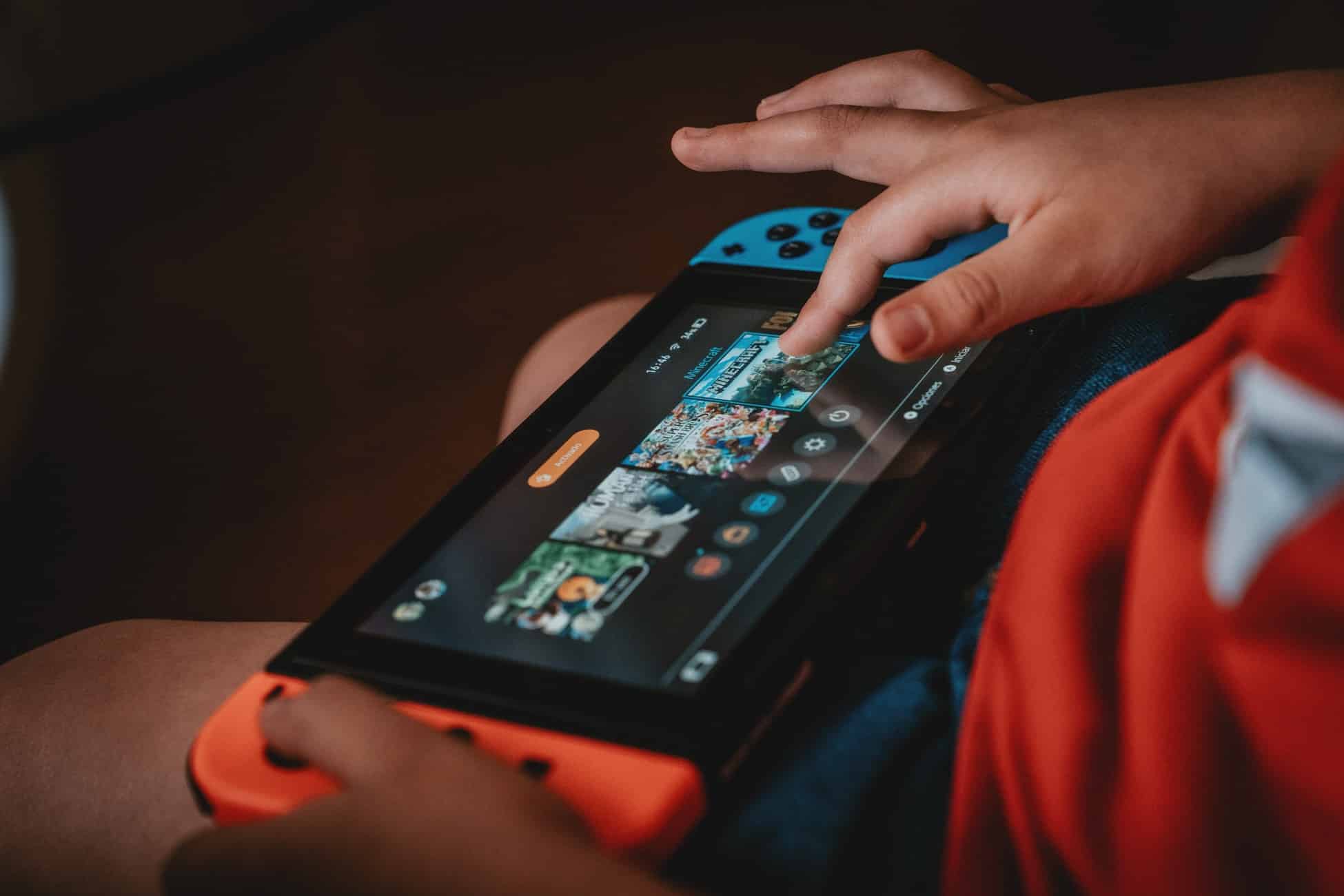 A child uses the touchscreen to select a game on a Nintendo Switch.