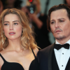 paparazzi photo shows Amber Heard in a black dress, standing next to Johnny Depp who is wearing a tuxedo