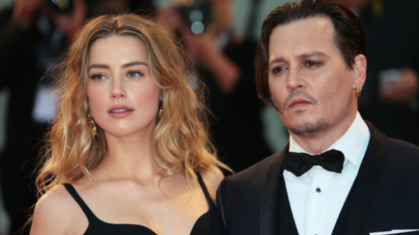 paparazzi photo shows Amber Heard in a black dress, standing next to Johnny Depp who is wearing a tuxedo