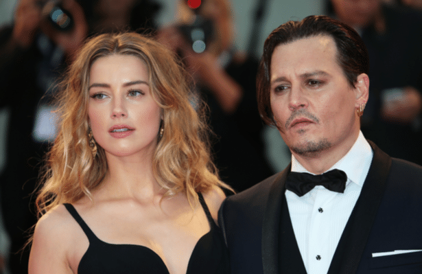 paparazzi photo shows Amber Heard in a black dress, standing next to Johnny Depp who is wearing a tuxedo