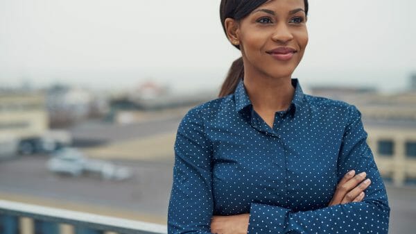 Confident happy Black woman standing outside with arms folded