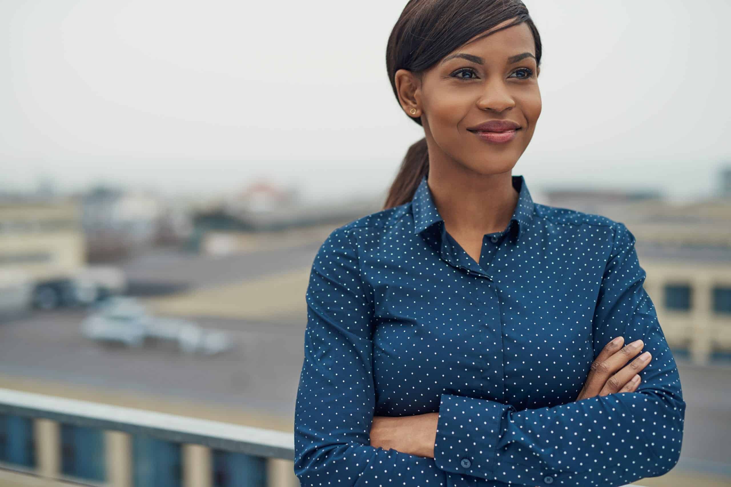 Confident happy Black woman standing outside with arms folded