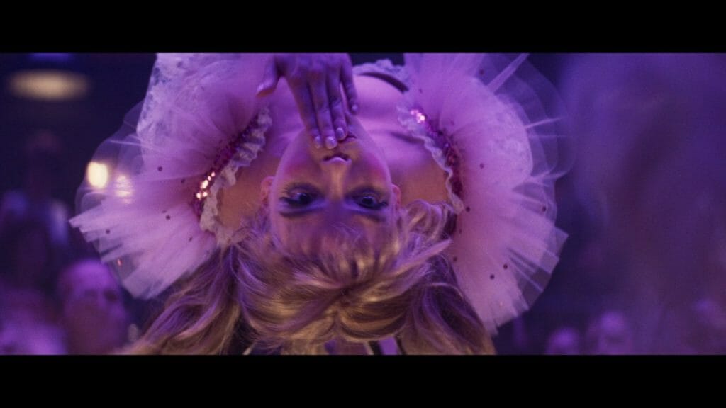 Screenshot from Edgar Wright's Last Night In Soho showing a female performer in a frilly dress hanging upside down