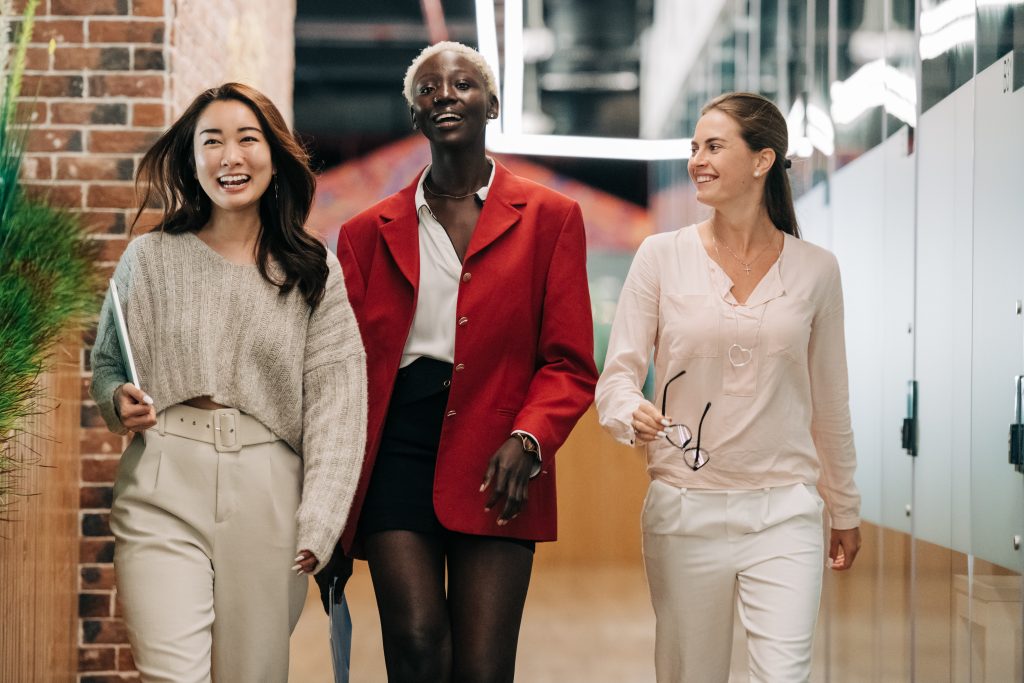An Asian woman, a Black woman, and a White woman walking together confidently at work