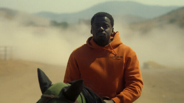 OJ (Daniel Kaluuya) rides a horse, with a cloud of dust in the background.