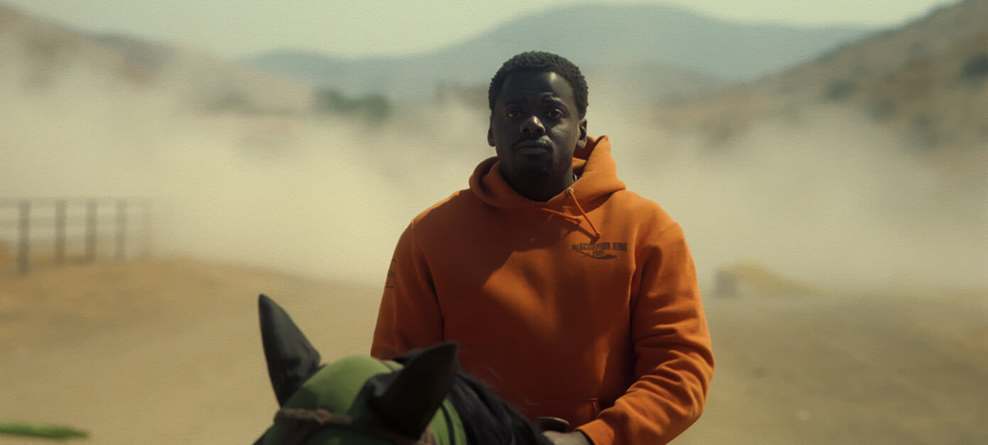OJ (Daniel Kaluuya) rides a horse, with a cloud of dust in the background.