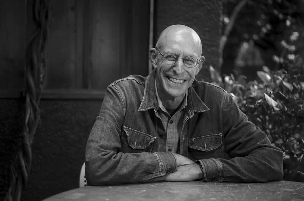 Michael Pollen smiling, sitting at table.