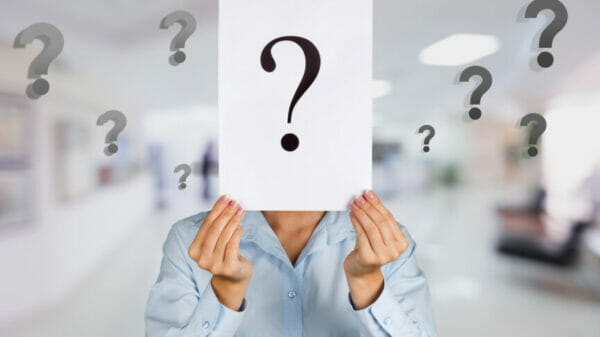 Person holding card with question mark in front of face
