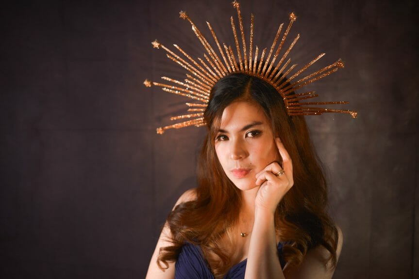 Woman wearing a beautiful elaborate gold headpiece staring thoughtfully