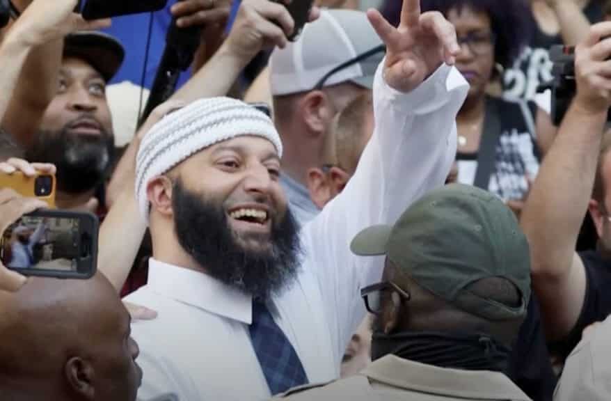 Syed celebrates his release in a crowd of journalists and supporters.