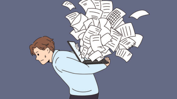 Cartoon of man carrying laptop with overflowing documents on his back