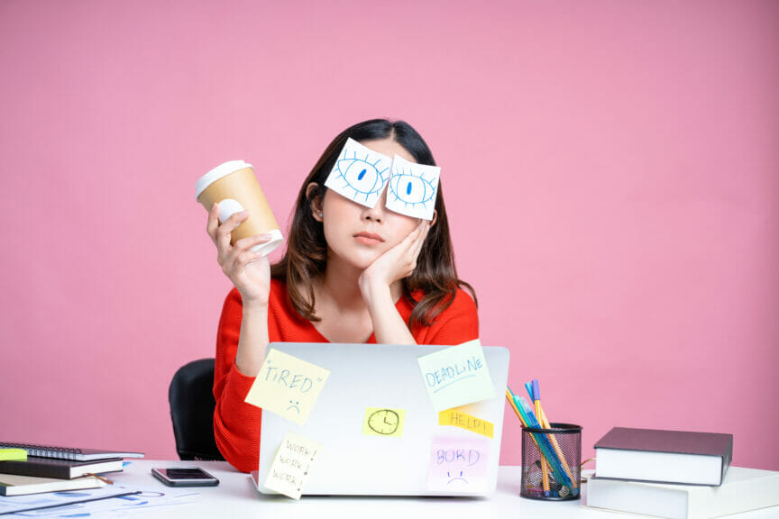 A woman holding a coffee cup bored with her numerous duties at work