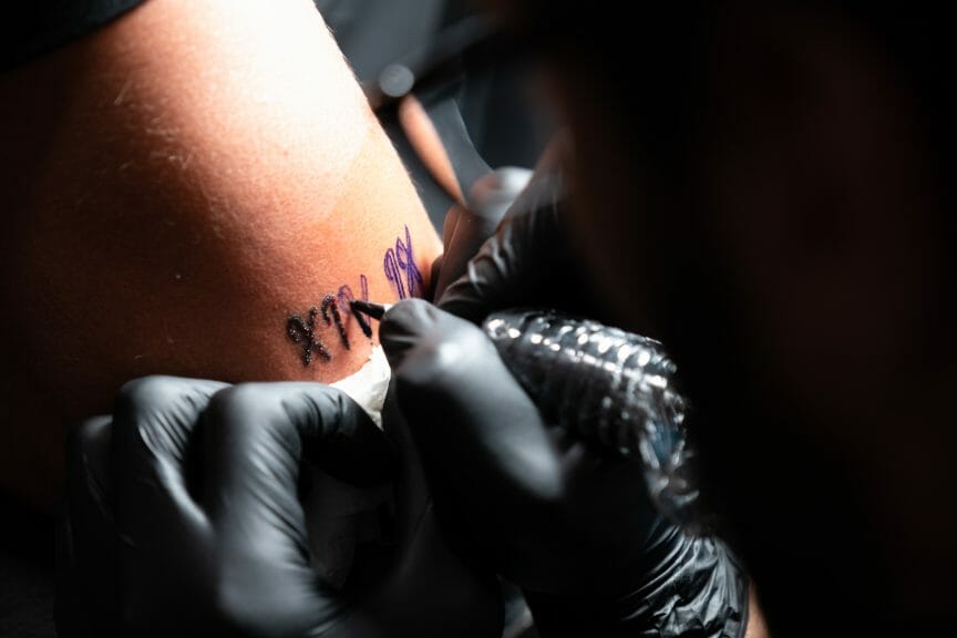 Artist tattooing roman numerals on client