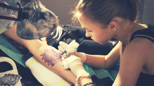 Artist tattooing client's arm