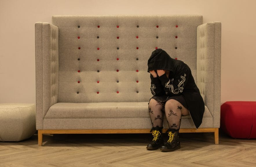 A student suffering from mental health issues cries on a sofa.