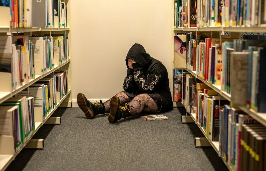 A student suffering from mental health issues is crying in the library.
