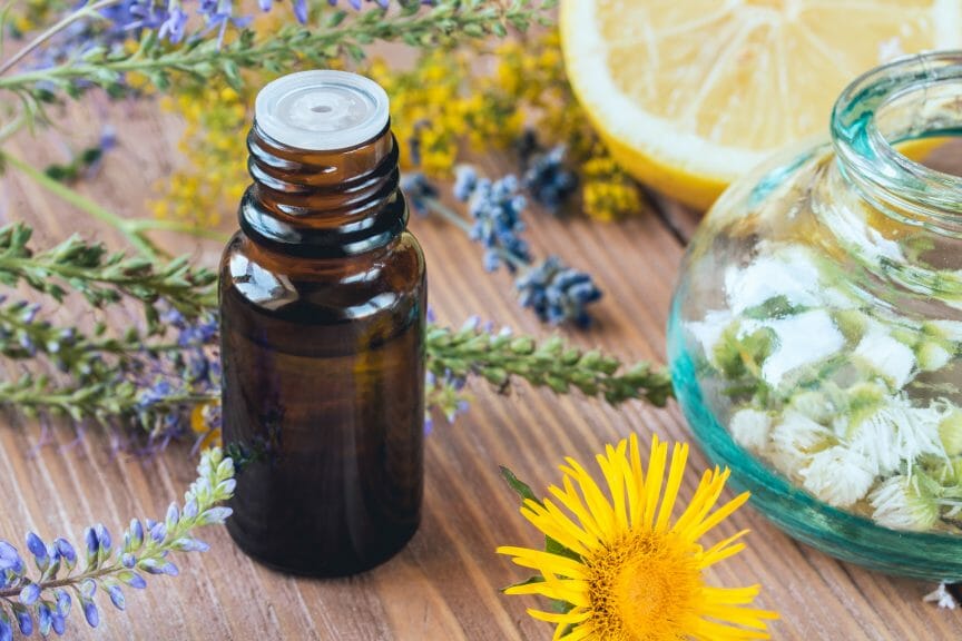 Essential oil bottle on wooden table with lemon and lavender in the background.
