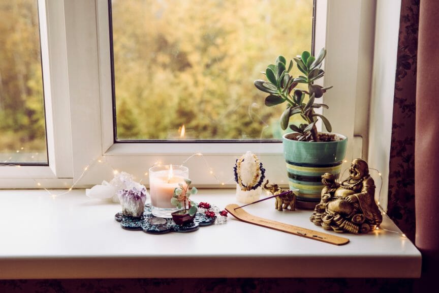 Incense, crystals, Budda statue, candle, and other spiritual tools and symbol on windowsill to increase positive energy.