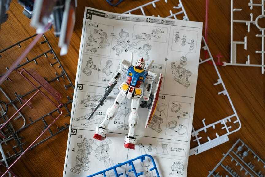 Plastic gundam modeling kit trays and instruction manual. An assembled gundam figurine. 