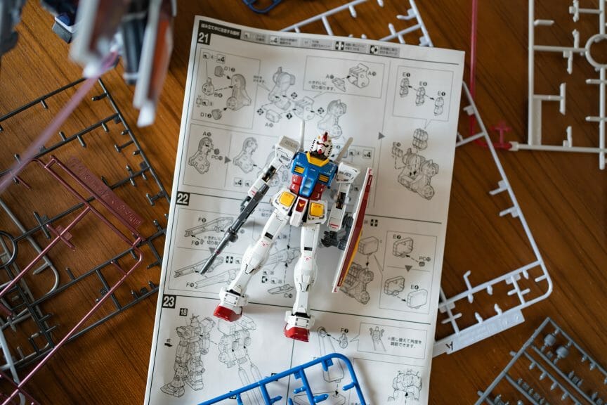 Plastic gundam modeling kit trays and instruction manual. An assembled gundam figurine.
