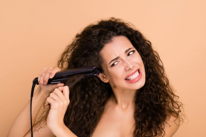 Woman using straightener on curly hair.