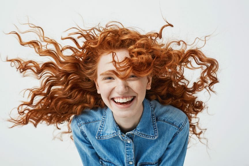 Woman with red curly hair smiling.