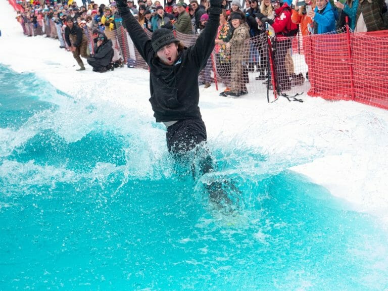 Snowboarder plunges into the ice water in an attempt to make it across the pool.
