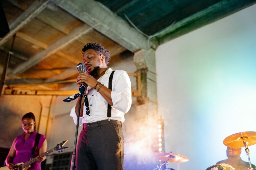 Man in white and black singing r&b on microphone.