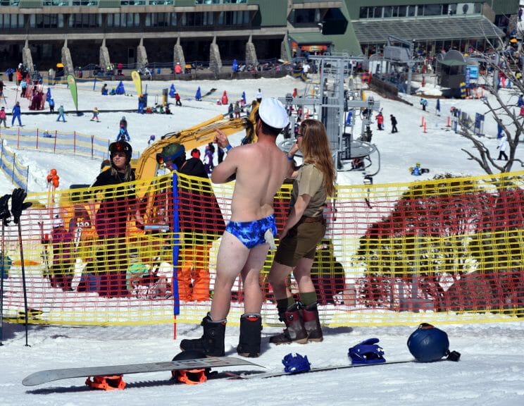 Pond skimming competitor at Perisher Resort in Australia standing on the side of a ski slope dressed in a shark speedo.