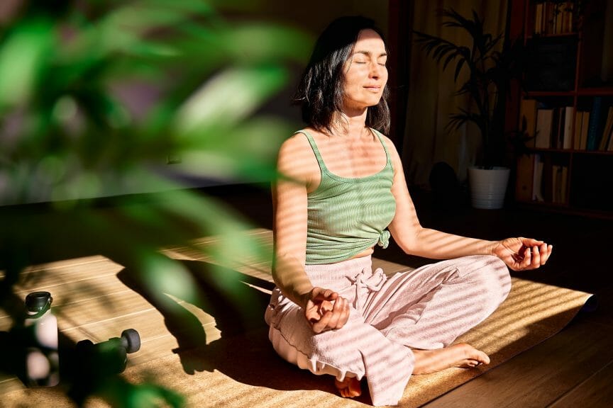 Woman meditating in the sunlight for mind-body connection.
