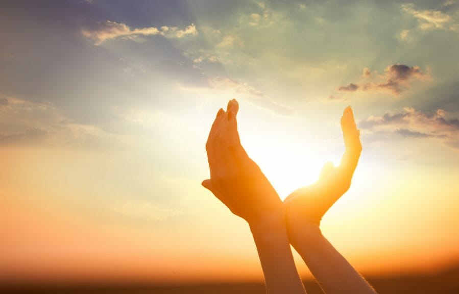 Person holding their hands up in the sunlight.