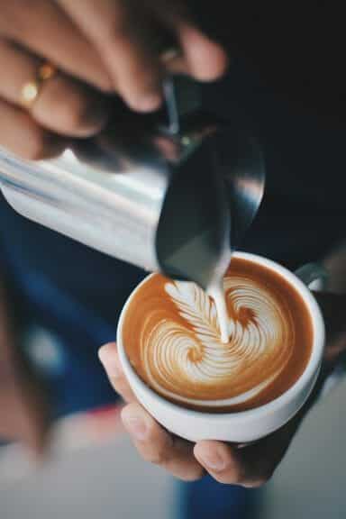 Steamed milk is slowly being poured into espresso to create a perfect Monk's head for a cappuccino.