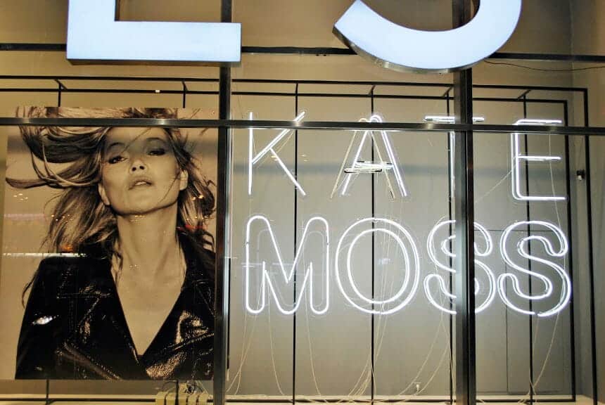 Photo showing the supermodel Kate Moss next to neon lights which read 'Kate Moss' - Thinspo and Bodychecking can be traced back to this movement 