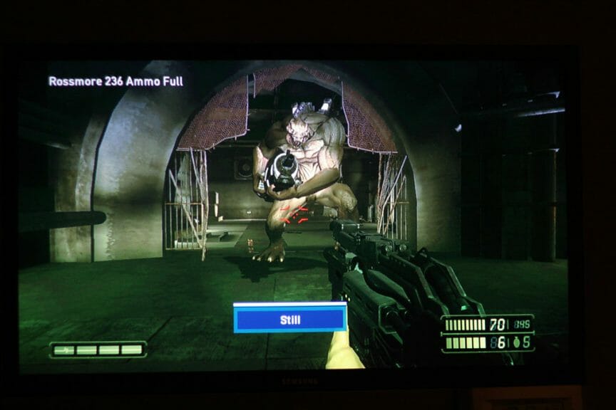 Screenshot from the game Resistance: Fall of Man with playable character holding a gun towards a giant titan monster from the game in the dark.