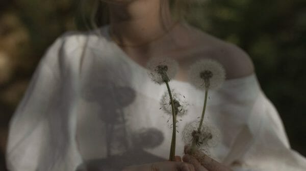 Woman in white dress holds flowers