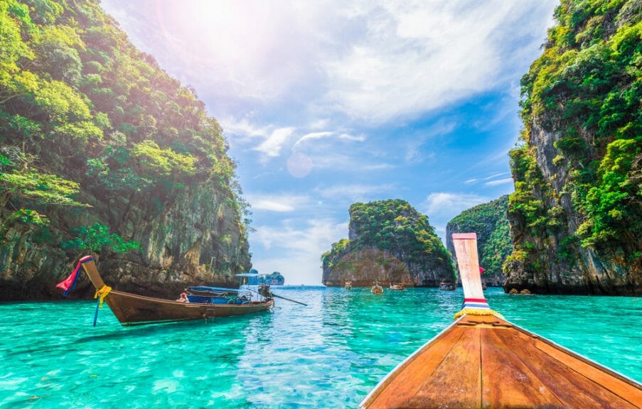 Phi Phi island, Thailand. Paddle boat in clear blue water with cliffs all around.