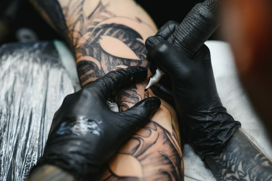 Tattoo artist working on someone's forearm.