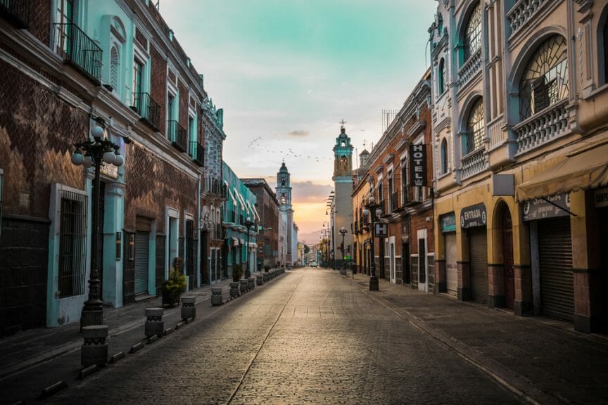 Street in Puebla, Mexico with colorful buildings lining the sidewalks. 
