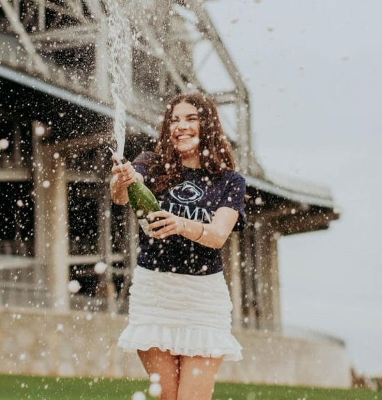 Amanda Taiano popping a bottle of champagne in celebration of graduating.