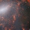 The image captured by the NIRCam instrument of the James Webb Space Telescope showcases the barred spiral galaxy NGC 5068, adorned with a vast assemblage of stars. The highest concentration of stars is found along the luminous central bar, accompanied by vibrant crimson gas clouds that are aglow, courtesy of youthful stars nestled within.