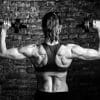 A women lifts hand-held weights with her muscular back toward the camera.