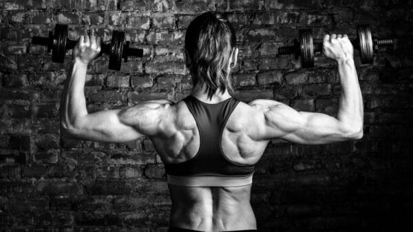 A women lifts hand-held weights with her muscular back toward the camera.