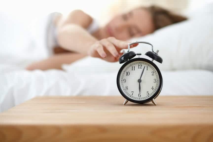 A college student snoozing their alarm before morning classes.