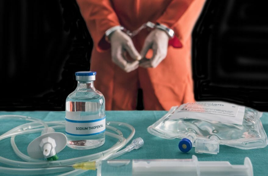 Prisoner handcuffed to death by lethal injection, vial with sodium thiopental and syringe on top of a table, conceptual image